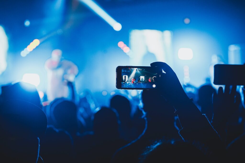 person taking picture on stage, showcasing live singer
